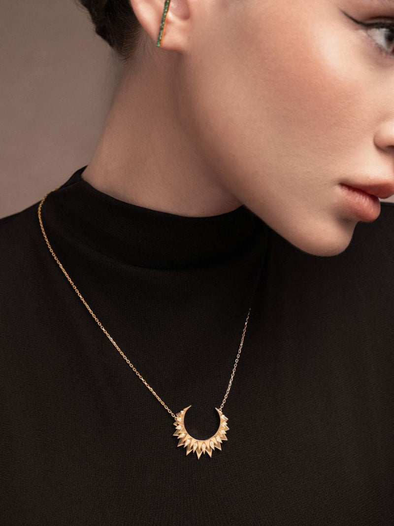 Close-up of a person wearing a gold necklace with a black background